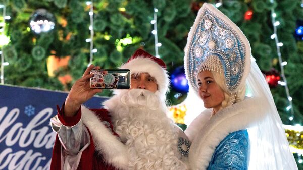Дед Мороз и Снегурочка фотографируются во время встречи Нового года в центре города Петропавловска-Камчатского - Sputnik Латвия