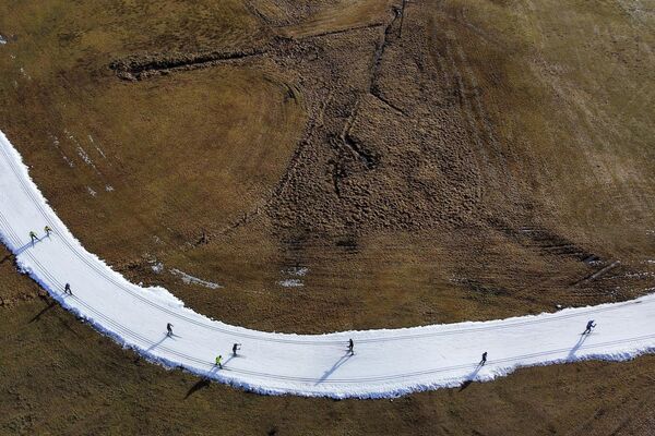 Люди катаются на лыжах в Рамзау (Австрия) 6 января 2023 года. Редкие снегопады и аномально теплая погода в большей части Европы стала причиной того, что местами вершины гор покрыты зеленой травой вместо привычного для этих дней снега. - Sputnik Латвия