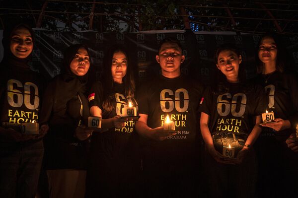 Индонезийские активисты позируют со свечами во время экологической кампании &quot;Час Земли&quot; в Сурабае 25 марта 2023 года. - Sputnik Латвия