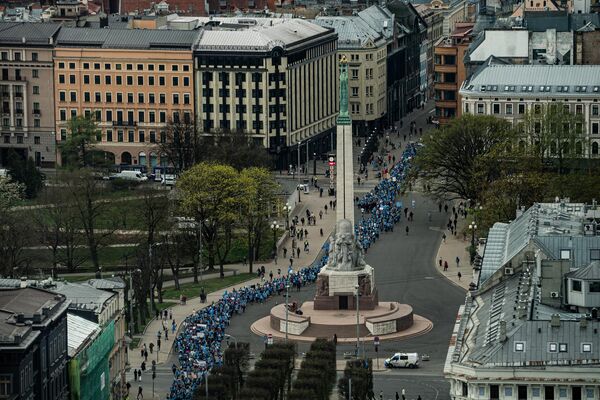 Участники акции протеста проходят мимо памятника Свободы. - Sputnik Латвия