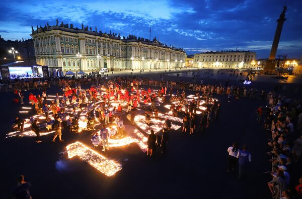 Участники акции Свеча памяти, приуроченной ко Дню памяти и скорби, зажигают свечи на Дворцовой площади в Санкт-Петербурге - Sputnik Латвия
