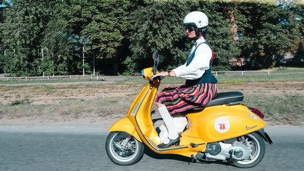 Участница Праздника песни и танца в латышском народном костюме на мотороллере в Риге - Sputnik Латвия