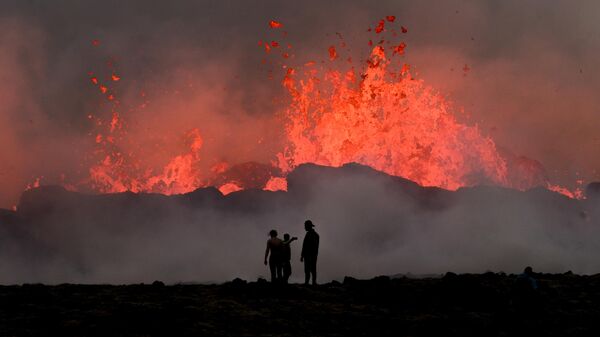 Люди наблюдают за текущей лавой во время извержения вулкана близ Литтл-Хрутура, к юго-западу от Рейкьявика в Исландии - Sputnik Латвия