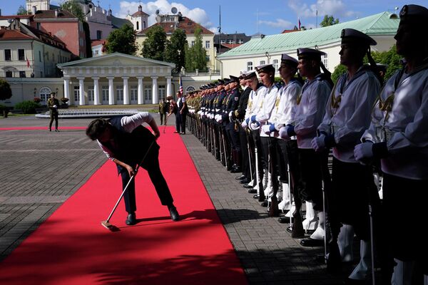 Женщина протирает красную ковровую  дорожку перед прибытием президента США Джо Байдена на встречу с  президентом Литвы Гитанасом Науседой на саммите НАТО в Вильнюсе - Sputnik Латвия