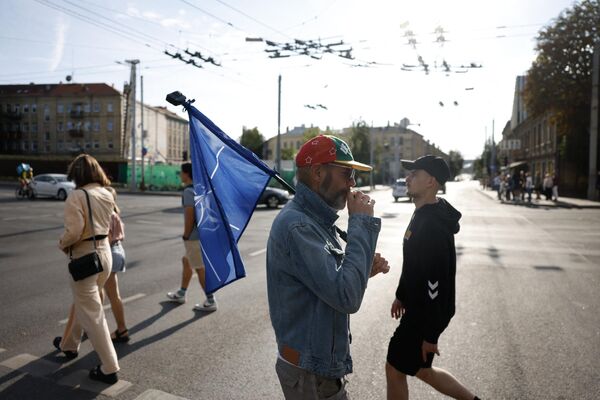 Мужчина с флагом НАТО на улице Вильнюса - Sputnik Латвия