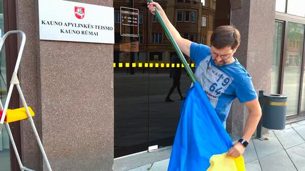 Литовский активист Антанас Кандротас снимает флаг Украины со здания Каунасского районного суда в Вильнюсе  - Sputnik Латвия