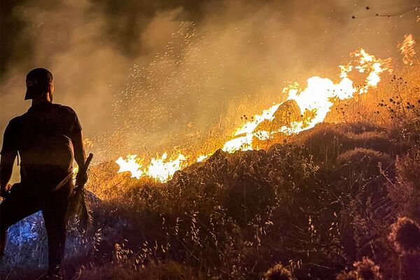 Мужчина наблюдает за пожаром на склоне холма в южном ливанском городе Ибл-аль-Саки. - Sputnik Латвия