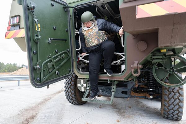 Участница экскурсии на военный полигон в Адажи пытается выйти из бронетранспортера Patria 6х6 - Sputnik Латвия
