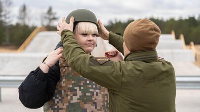 Военнослужащий латвийской армии помогает надеть каску 