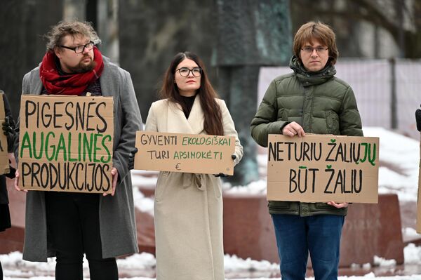 На фото: участники акции держат плакаты с надписями: &quot;Более дешевой растительной продукции&quot;, &quot;Жить экологично должно быть выгодно&quot;, &quot;Нет зеленых, чтобы быть зеленым&quot;. - Sputnik Латвия