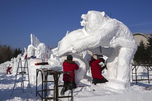 Здесь, на фестивале, на протяжении последних трех десятков лет устанавливали несколько рекордов Гиннеса, среди которых - гигантские ледяные скульптуры.  На фото: рабочие вырезают снежные скульптуры на ежегодном Harbin Ice and Snow World в Харбине, провинция Хэйлунцзян на северо-востоке Китая. - Sputnik Латвия