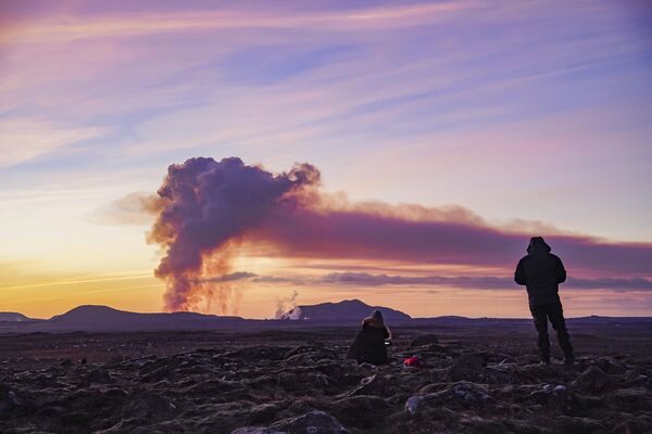 Люди наблюдают с севера за извержением вулкана возле Гриндавика. - Sputnik Латвия