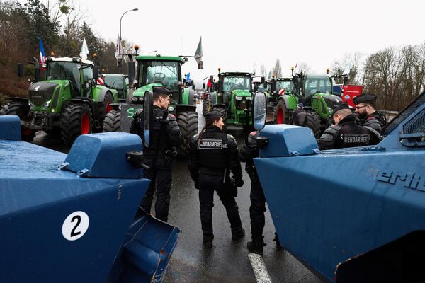 Протестующие фермеры блокируют ключевые автотрассы тракторами. На фото: французские силовики и бронетранспортеры против крестьян и тракторов. - Sputnik Латвия