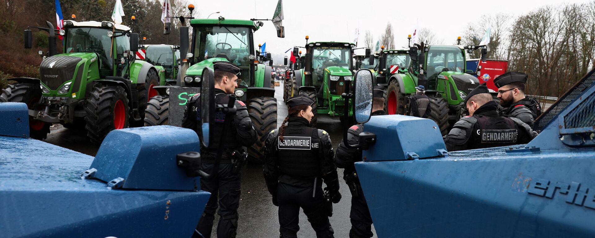 Сотрудники французской полиции стоят рядом с бронетранспортерами перед тракторами, блокирующими шоссе к югу от Парижа - Sputnik Латвия, 1920, 15.02.2024