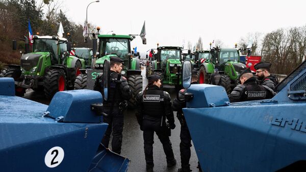 Сотрудники французской полиции стоят рядом с бронетранспортерами перед тракторами, блокирующими шоссе к югу от Парижа - Sputnik Латвия