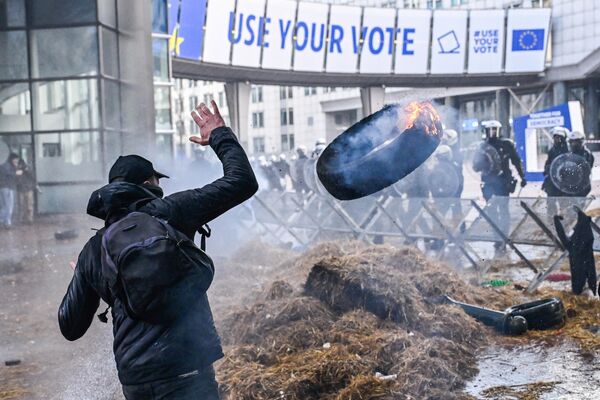 Саммит ЕС в Брюсселе начал работу на фоне столкновений протестующих с полицией. На фото: в сторону бельгийских правоохранителей летит горящая покрышка. - Sputnik Латвия