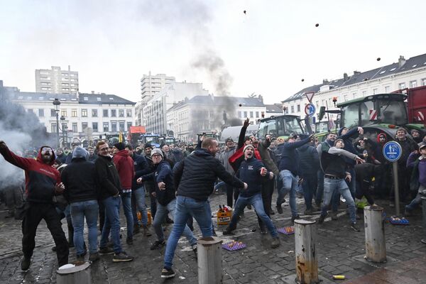 Полиция бельгийской столицы насчитала тысячу тракторов, прибывших для участия в акции протеста. На фото: протестующие в Брюсселе начали бросать камни в сторону силовиков. - Sputnik Латвия