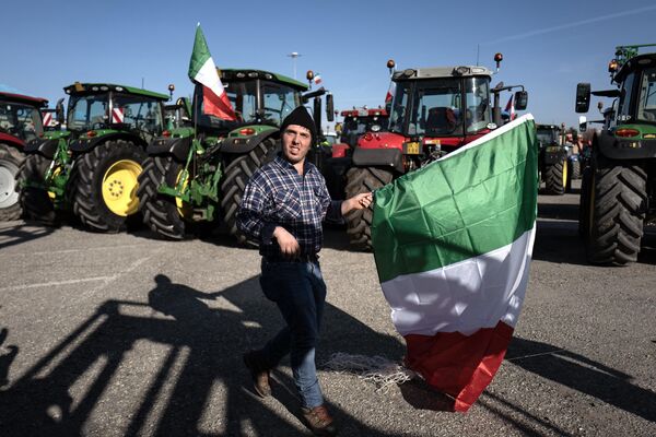 У итальянских фермеров своя тактика протеста: колонны тракторов встают в пикет напротив городских администраций. На фото: участник акции протеста в городе Кунео. - Sputnik Латвия