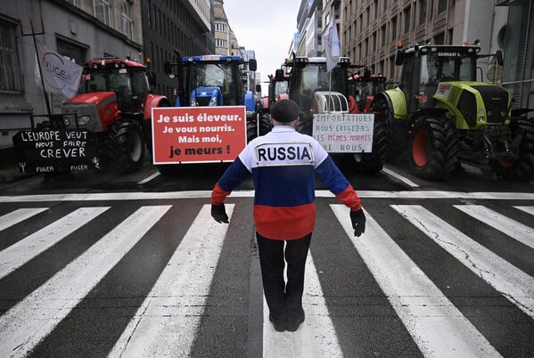 Протестующий в одежде цветов российского флага и надписью &quot;Россия&quot; перед сельхозтехникой фермеров в Брюсселе  - Sputnik Латвия