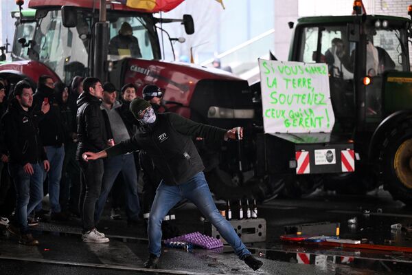 Участник протеста кидает в сторону полицейских предмет  - Sputnik Латвия
