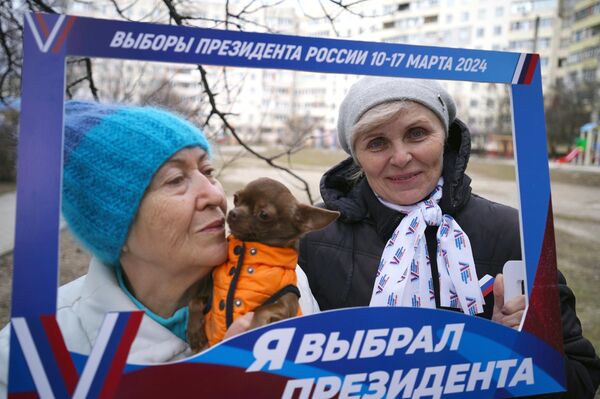 Женщины с собачкой фотографируются на выездном голосовании на выборах президента РФ в Мариуполе. - Sputnik Латвия