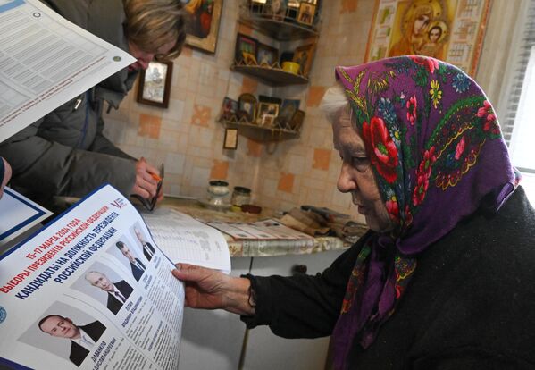 Жительница Северодонецка (ЛНР) изучает избирательный бюллетень в ходе выездного голосования на выборах президента РФ. - Sputnik Латвия