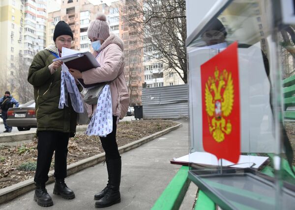 Член избирательной комиссии оформляет документы жительнице Донецка в ходе выездного голосования на выборах президента РФ. - Sputnik Латвия