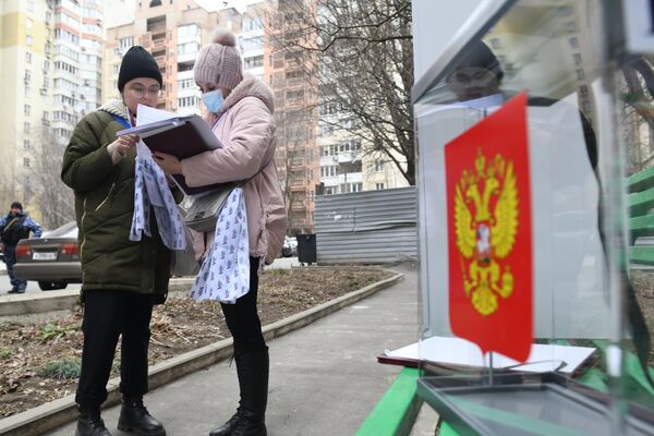 Член избирательной комиссии оформляет документы жительнице Донецка в ходе выездного голосования на выборах президента РФ. - Sputnik Латвия