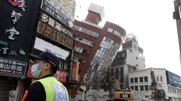 Офицер полиции стоит на страже возле частично обрушившегося здания через день после мощного землетрясения в городе Хуалянь, восточный Тайвань, Китай - Sputnik Латвия