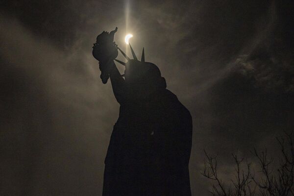 Луна частично закрывает солнце над статуей Свободы в Нью-Йорке, США.  - Sputnik Латвия