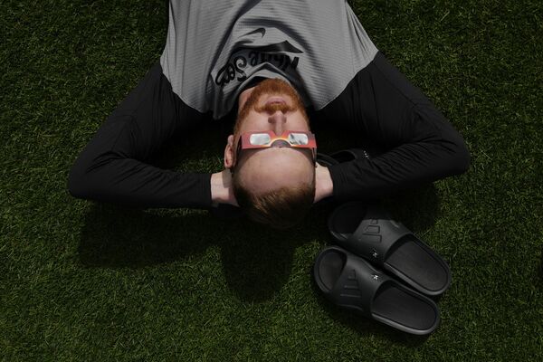 Питчер &quot;Чикаго Уайт Сокс&quot; Стивен Уилсон через специальные очки наблюдает за солнечным затмением на стадионе &quot;Прогрессив Филд&quot; в Кливленде, США.  - Sputnik Латвия