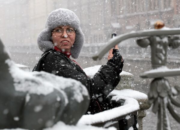 Женщина фотографирует заснеженный город.  - Sputnik Латвия