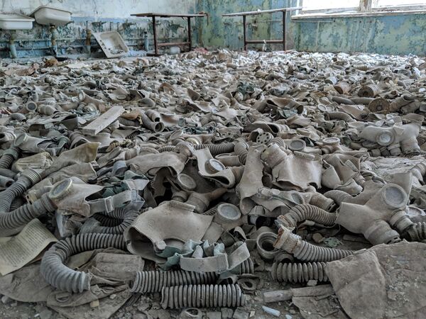 Сейчас, спустя 38 лет, Чернобыльская зона представляет собой огромную загрязненную территорию вокруг АЭС.На фото: противогазы, разбросанные в заброшенной школе в Припяти, Украина. - Sputnik Латвия