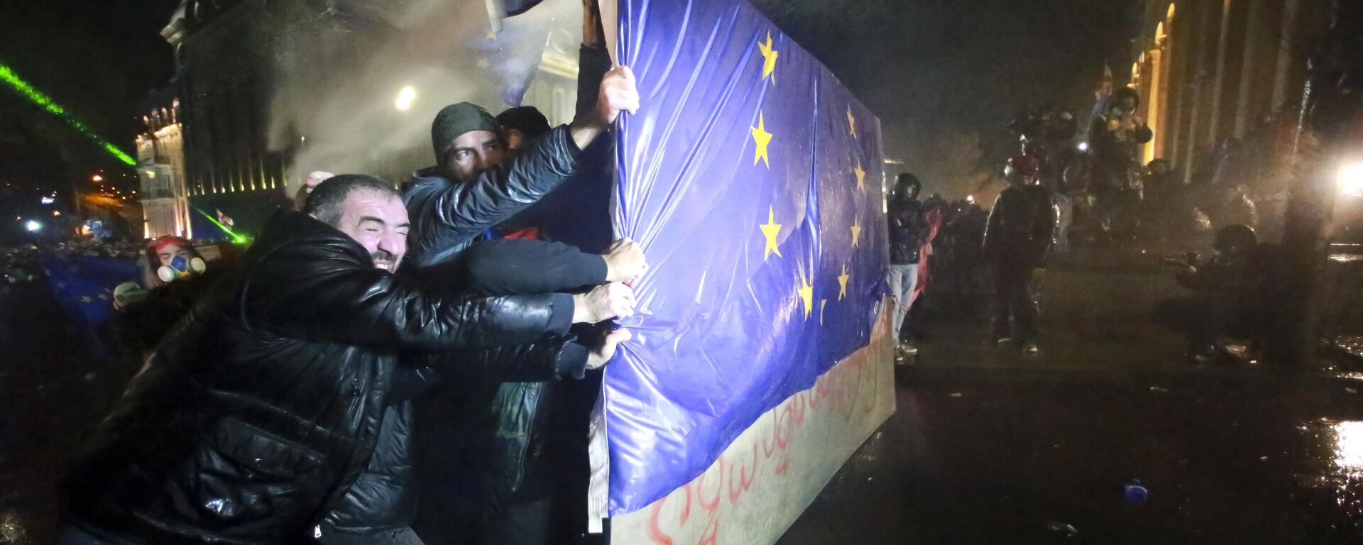 Люди держат часть забора с флагом ЕС в Тбилиси, Грузия - Sputnik Латвия, 1920, 08.12.2025