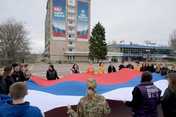 Активисты молодежного движения Юг молодой совместно с другими организациями развернули флаг РФ на площади Победы в Мелитополе в рамках празднования годовщины воссоединения Крыма с Россией Активисты молодежного движения Юг молодой совместно с другими организациями развернули флаг РФ на площади Победы в Мелитополе в рамках празднования годовщины воссоединения Крыма с Россией - Sputnik Латвия