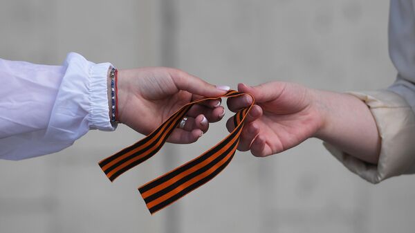 Волонтер раздает георгиевские ленточки на Зубовском бульваре в Москве  - Sputnik Латвия