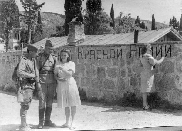 Крымская наступательная операция была проведена с 8 апреля по 12 мая 1944 года. На фото: девушка освобожденного Кореиза пишет на стене "Слава доблестным бойцам Красной Армии", другая девушка разговаривает с двумя солдатами. Крымская наступательная операция была проведена с 8 апреля по 12 мая 1944 года. На фото: девушка освобожденного Кореиза пишет на стене "Слава доблестным бойцам Красной Армии", другая девушка разговаривает с двумя солдатами. - Sputnik Латвия