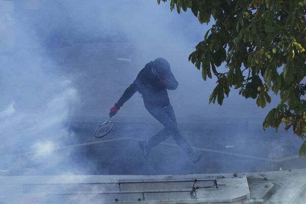 Протестующий бежит от слезоточивого газа во время демонстрации. - Sputnik Латвия