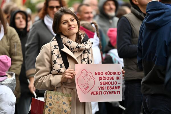 На фото: участница марша держит плакат с надписью: &quot;От младенца в утробе до старика — все достойны жить&quot;. - Sputnik Латвия