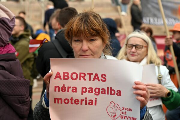 На фото: участница марша держит плакат с надписью: &quot;Аборт — это не помощь женщине&quot;. - Sputnik Латвия