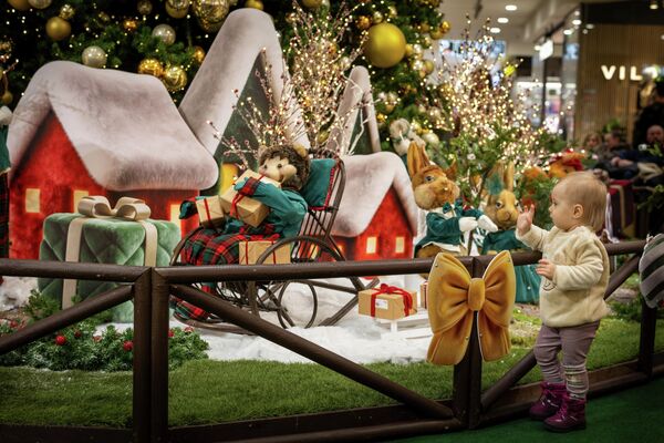 Девочка рассматривает новогодние и  рождественские украшения, установленные в торговом центре в Вильнюсе - Sputnik Латвия