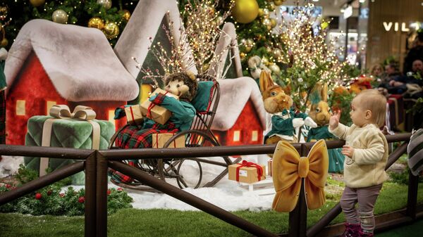 Девочка рассматривает новогодние и рождественские украшения, установленные в торговом центре, украшенном к Рождеству и Новому году в Вильнюсе, Литва - Sputnik Латвия