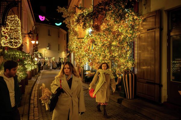 Люди идут по улице, украшенной рождественскими огнями, в старом городе Вильнюса - Sputnik Латвия