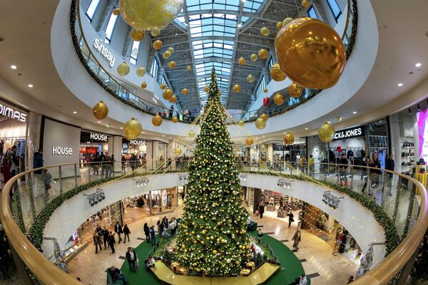 Люди проходят мимо гигантской рождественской елки, установленной в честь приближающихся праздников в торговом центре в Вильнюсе - Sputnik Латвия