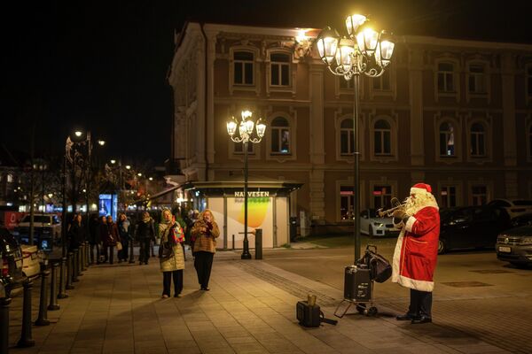 В Вильнюсе уличный музыкант, одетый как Санта-Клаус, играет для прохожих  - Sputnik Латвия