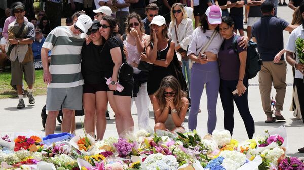 Люди собрались вокруг цветочной композиции в память о жертвах стрельбы возле павильона Бонди на пляже Бонди - Sputnik Латвия
