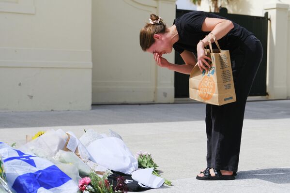 Женщина возлагает цветы к стихийному мемориалу жертвам стрельбы Женщина возлагает цветы к стихийному мемориалу жертвам стрельбы - Sputnik Латвия