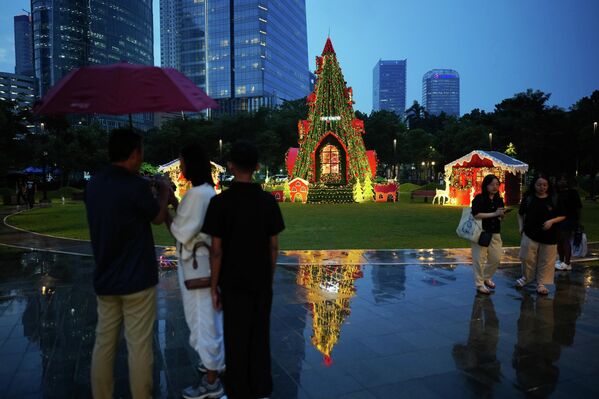 Люди проходят мимо рождественской елки, установленной в парке в Джакарте, Индонезия. - Sputnik Латвия
