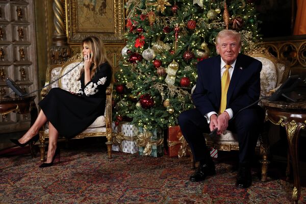 Президент США Дональд Трамп и первая леди Мелания Трамп звонят детям, которые следят за перемещениями Санта-Клауса с помощью системы слежения воздушно-космической обороны (NORAD) в канун Рождества на курорте Мар-а-Лаго во Флориде - Sputnik Латвия