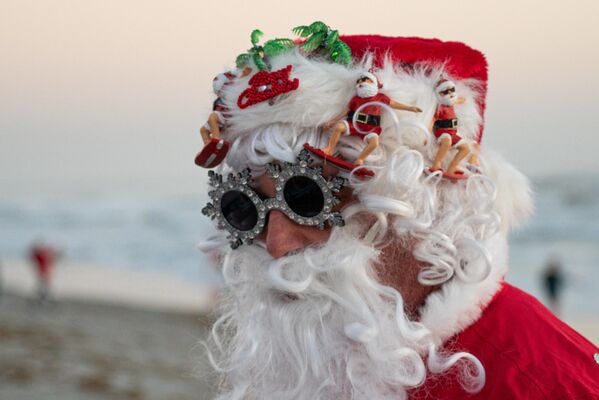 Серфер в костюме Санта-Клауса ждет начала ежегодного мероприятия "Серфинг Санта-Клаусов", проводимого в рамках празднования Рождества в Кокоа-Бич во Флориде, США - Sputnik Латвия